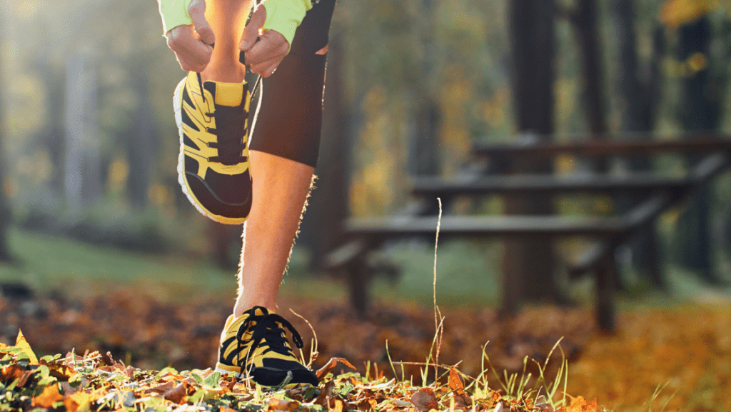 runner tying laces in autumn wood, preparing for long-distance running